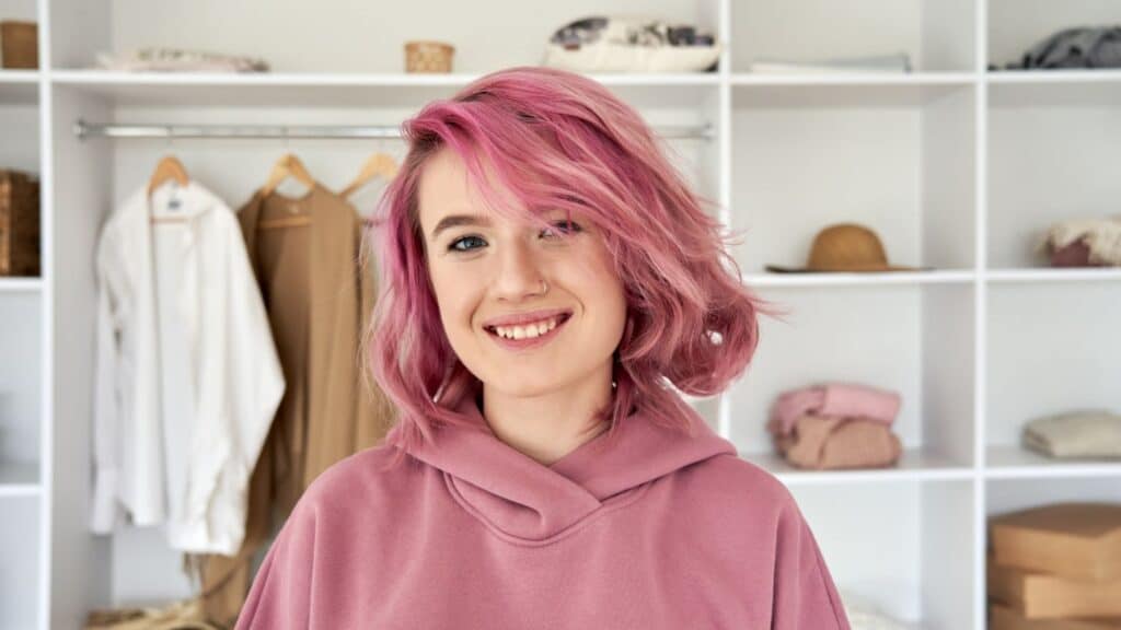A young woman customer with pink hair in a clothing boutique.