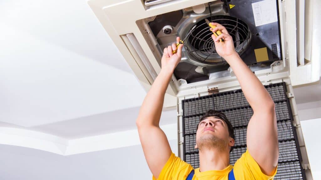 Apartment repair worker fixes a ventilation fan.